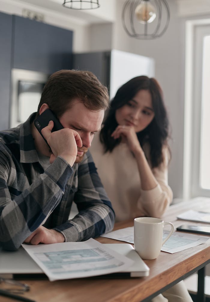 Mastering the First Impression: Your intriguing post title goes here A worried couple sits at a table with bills and a phone, planning their finances.